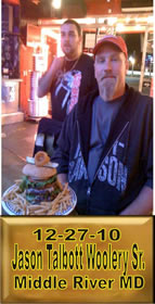 Cup Burger Challenge finisher holding their gold name plaque at Cruisin Café
