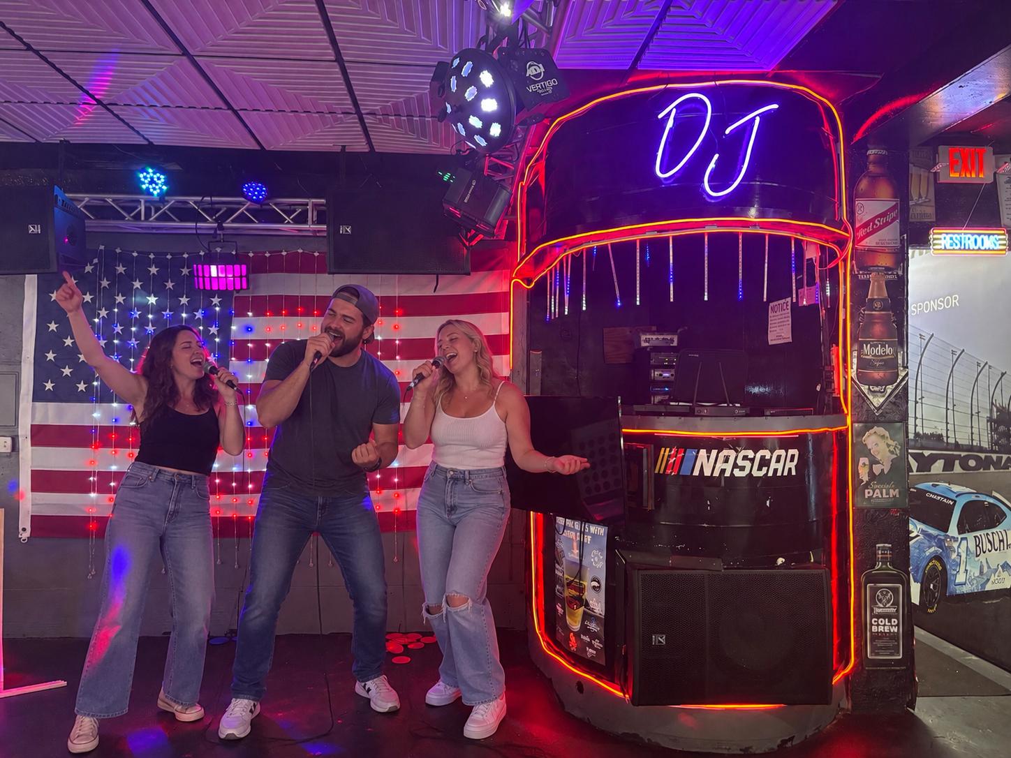 Guests singing karaoke under the neon DJ booth at Cruisin Café
