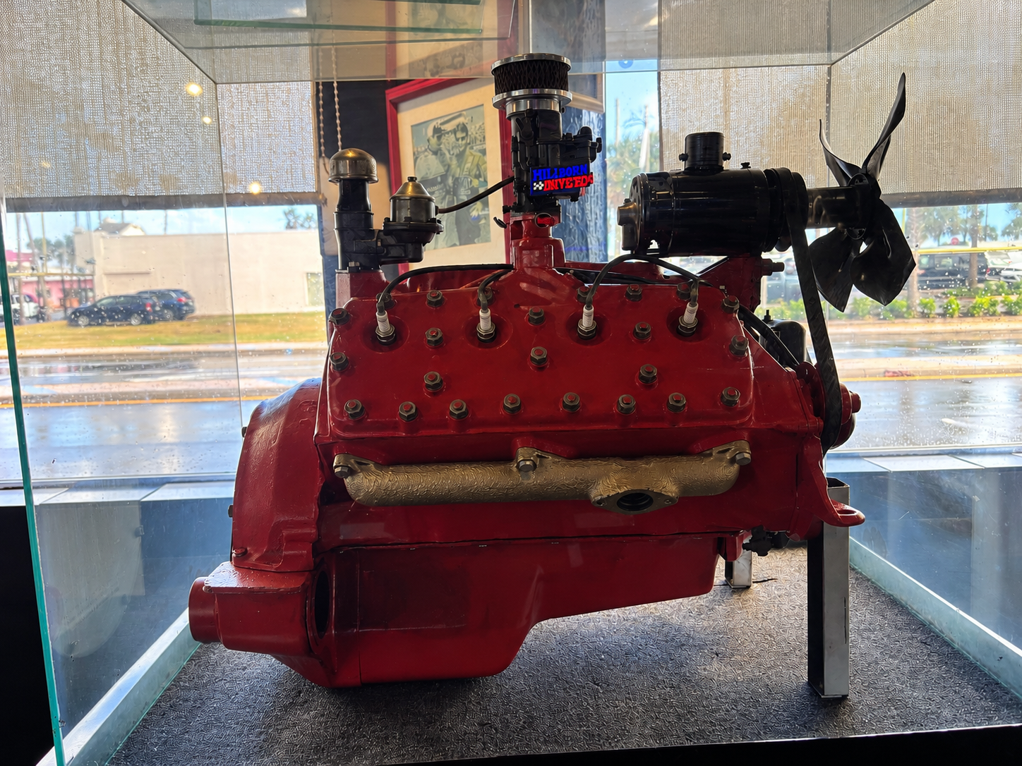 Vintage red flathead V8 race engine displayed in a glass case at Cruisin Café